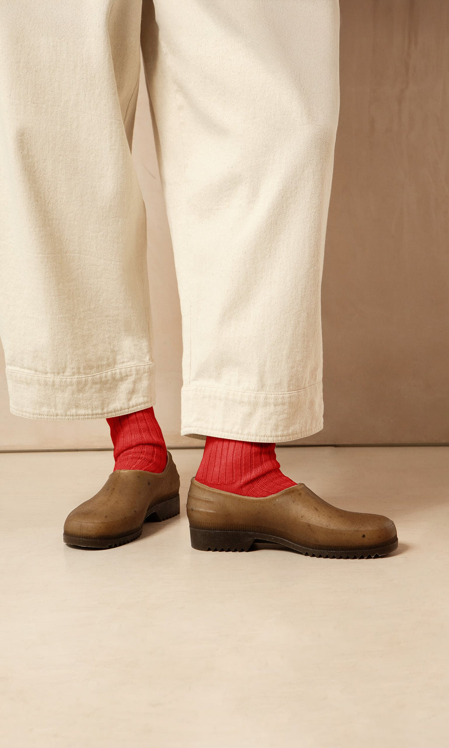 Plümo- Person wearing wide cream pants, bright red socks, and Hemp Clogs, standing on a light floor.