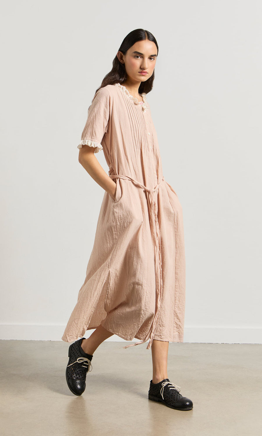 Plümo- A person in the Heide Dress—a pink ticking stripe vintage midi with pockets—stands against a plain, light background.
